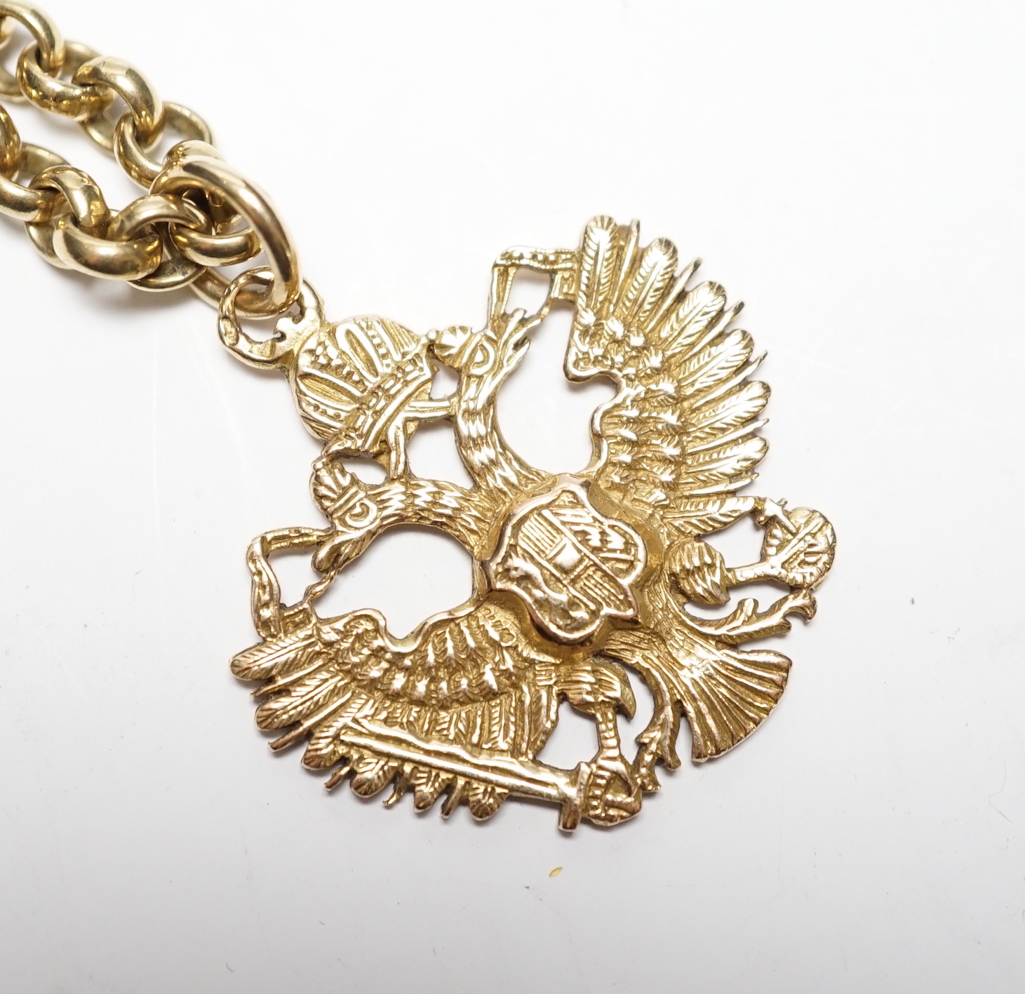 An Austrian yellow metal double eagle pendant, width 31mm, on a 9ct gold belcher link chain, 62cm, gross weight 52.1 grams.